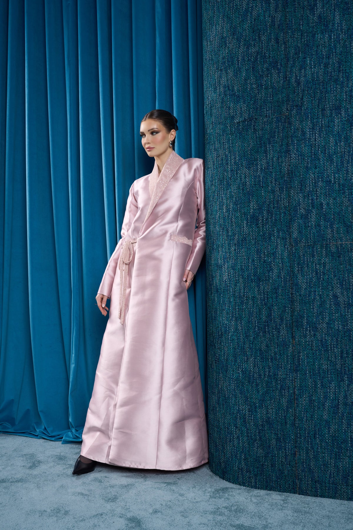 Hissa Line blush satin abaya beside the original blue curtain